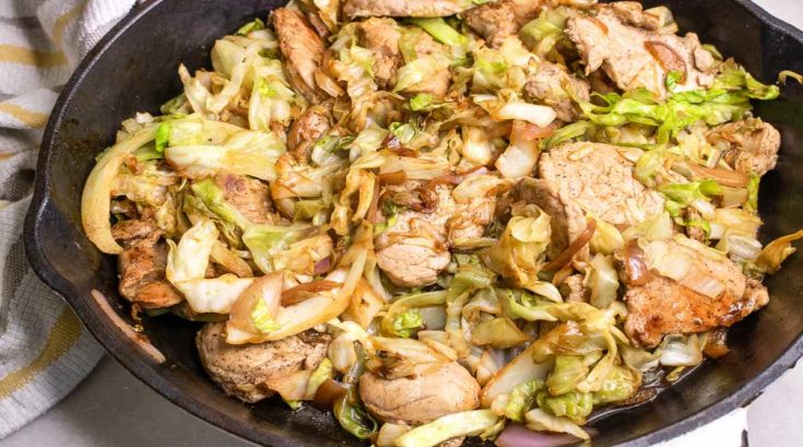Sauteed red onions, and sliced cabbage with pan seared slices of pork in a cast iron skillet