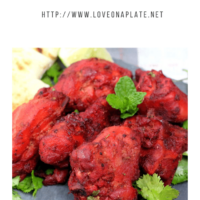 pieces of Tandoori chicken on a slate platter with pieces of naan cut into quarter
